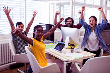 imagem de equipe de funcionários em suas mesas comemorando